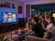 Friends enjoying tg88 live casino games at home, vibrant screens, snacks, and cozy atmosphere.